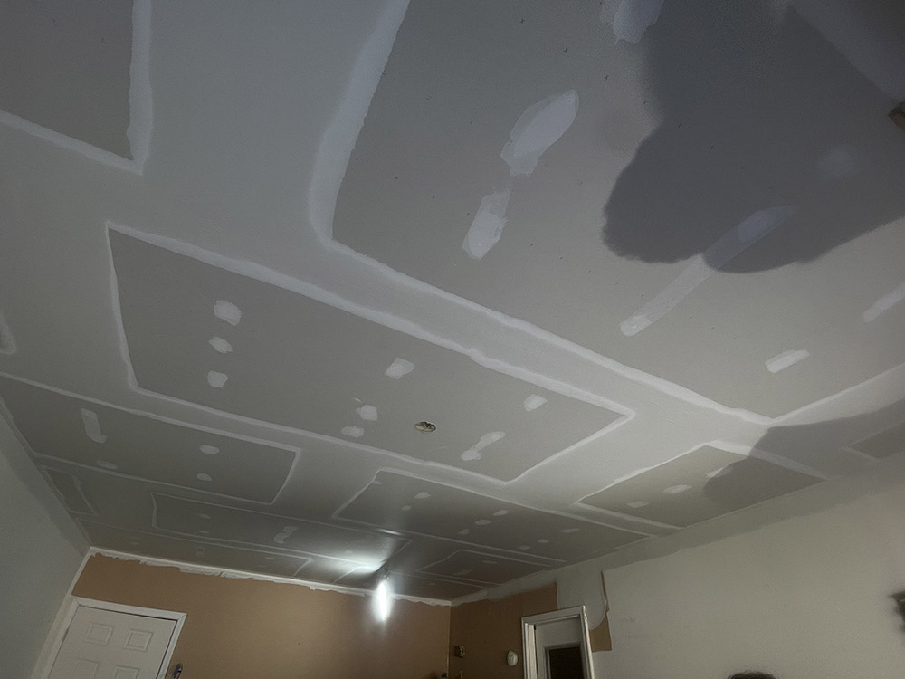 Wide feathered joint compound passes across garage ceiling butt joints